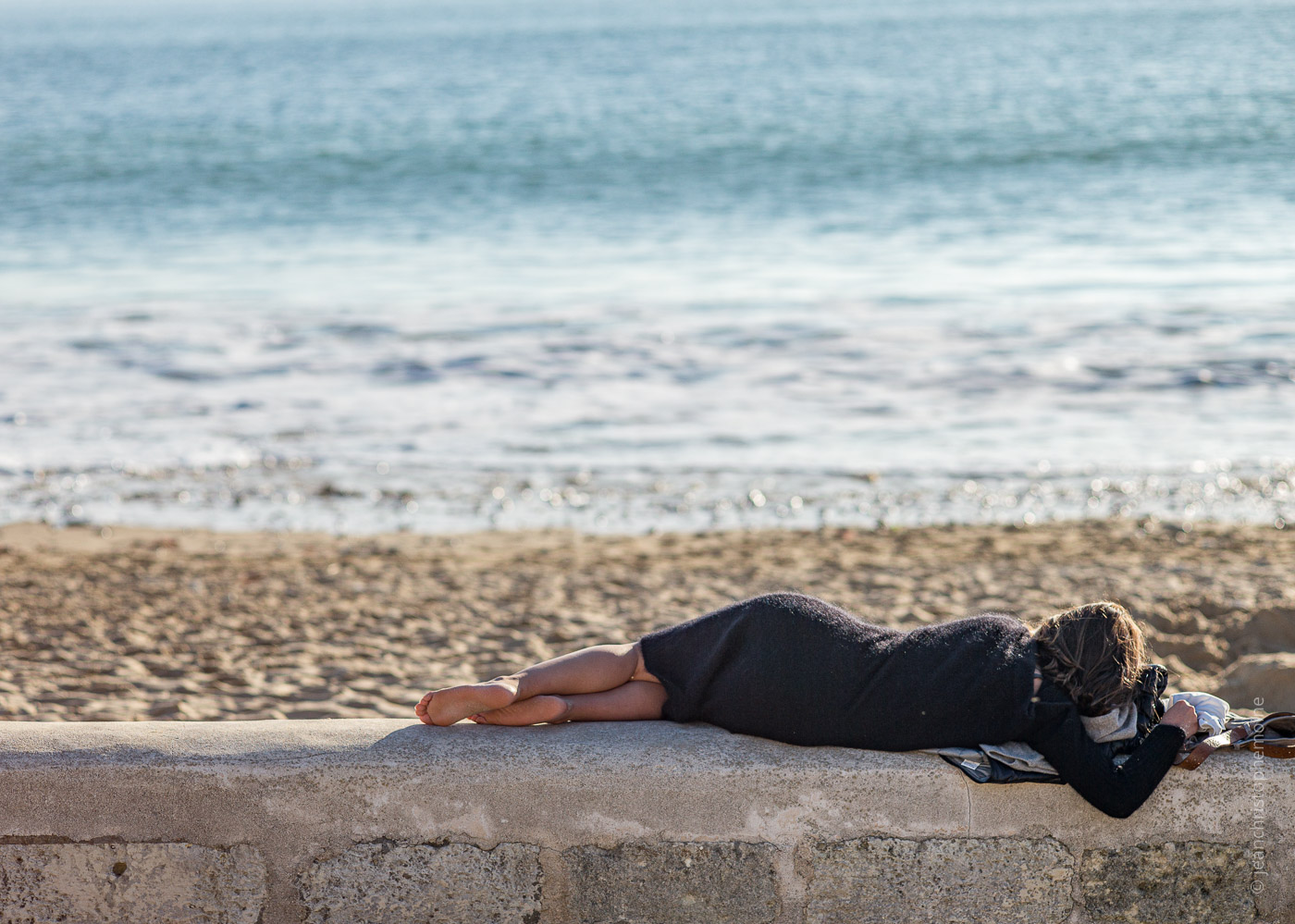 Une jeune femme allongée devant l'océan