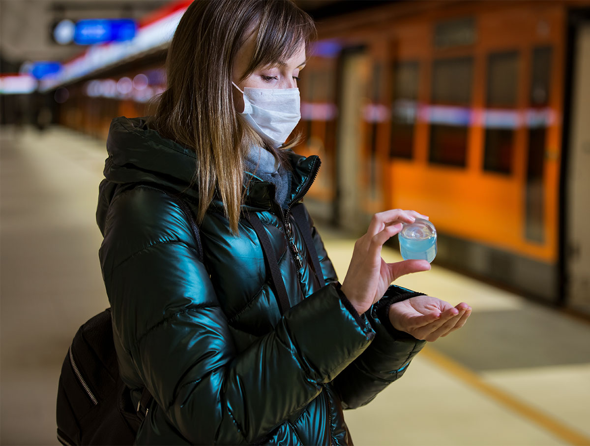 Jeune femme désinfectant des mains avec une solution hydroalcoolique dans le métro