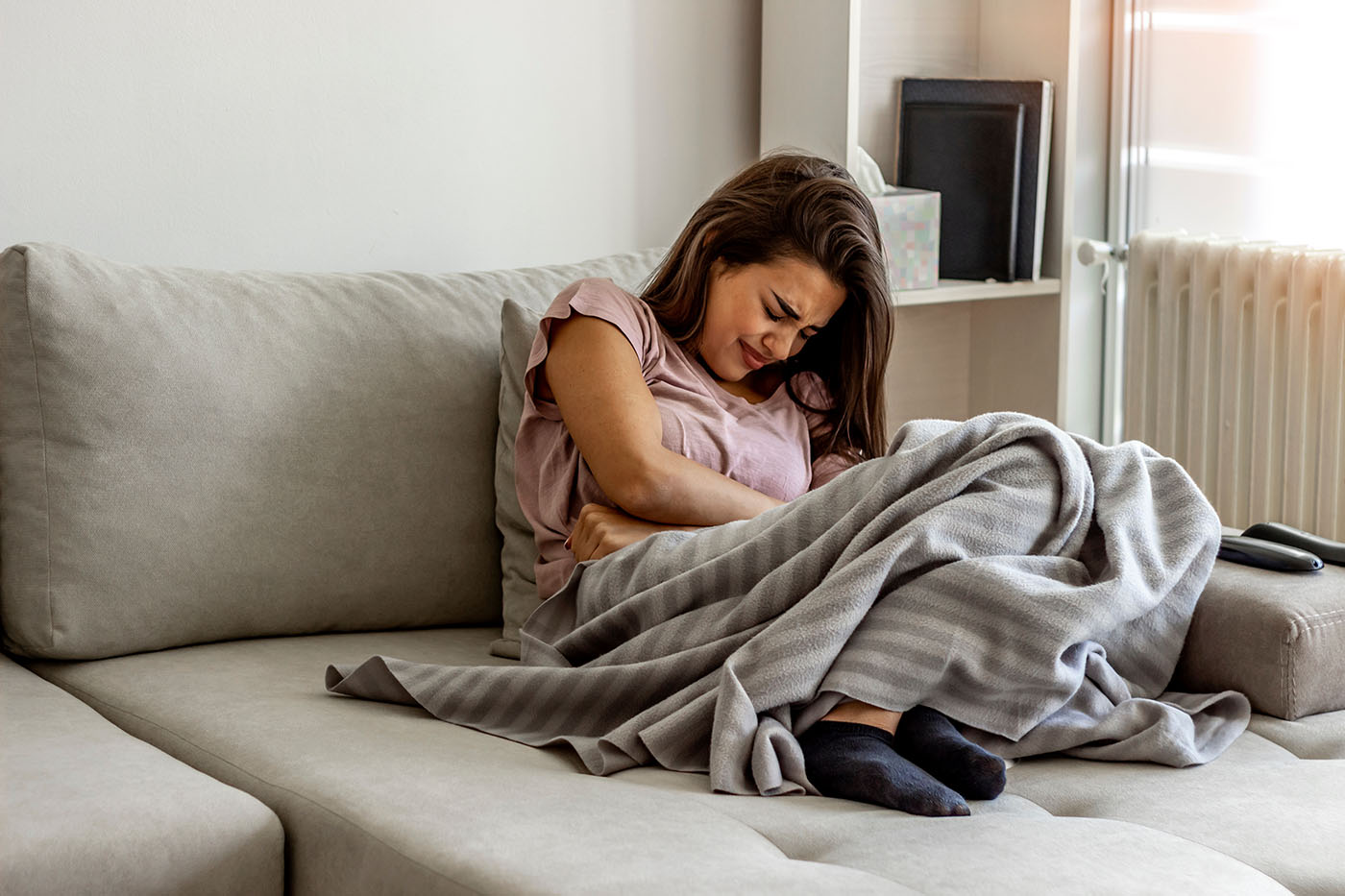 Unhappy woman holding hands on stomach suffering from abdominal pain with eyes closed. Women having menstrual period, food poisoning, gastritis or diarrhea. Girl feeling unwell sitting in living room.
endométriose une maladie complexe
