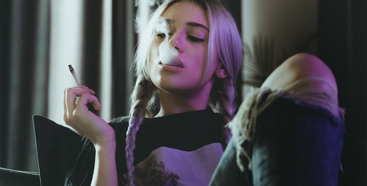Une jeune fille fume assise dans un canapé