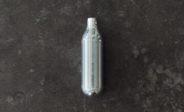 A high angle shot of a nitrous oxide capsule on a concrete surface